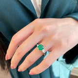 Cushion Cut Emerald and Pear-Shaped Diamond Three-Stone Ring on a Hand