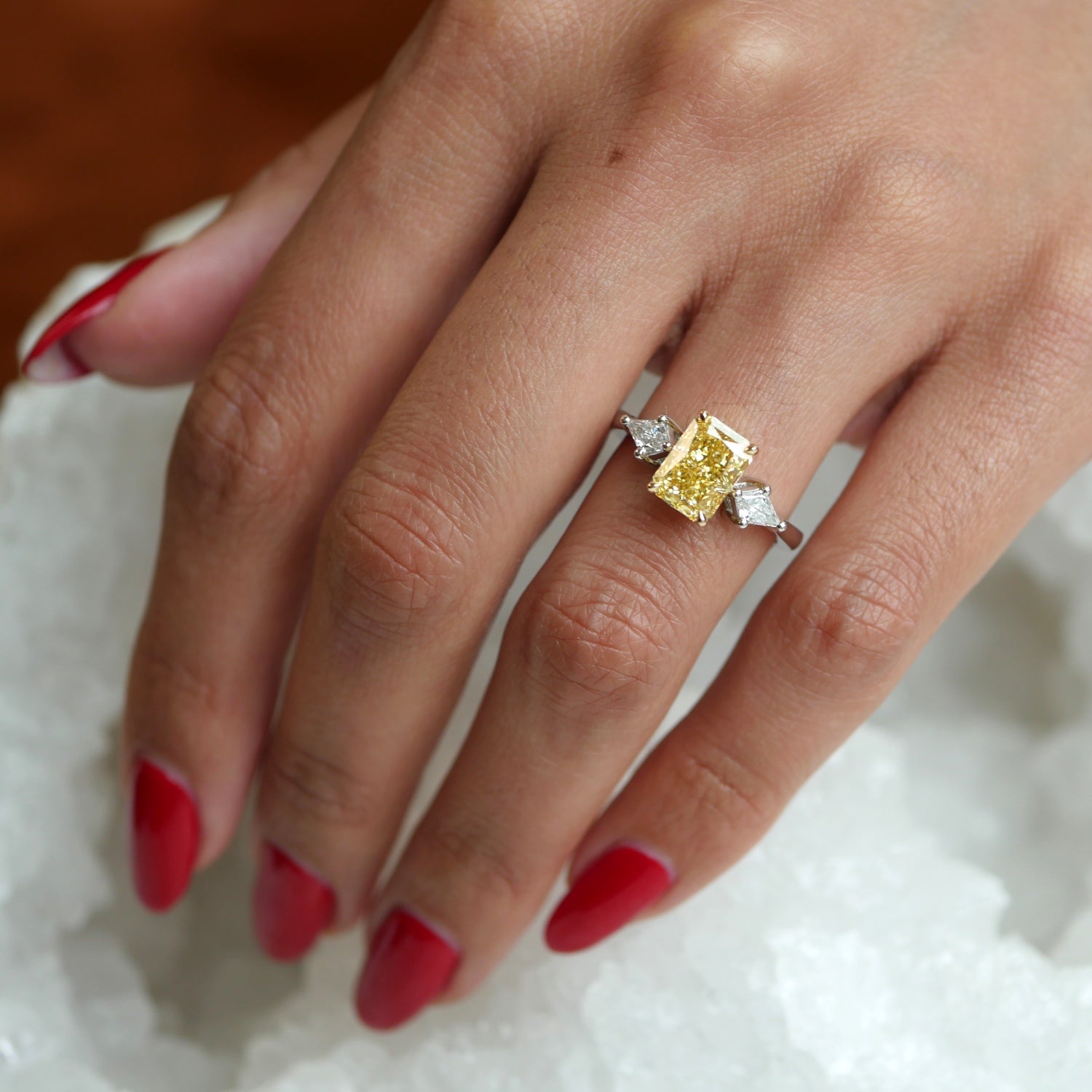 Radiant Cut Fancy Yellow Lab-Grown Diamond and Kite Side Stone Three-Stone Engagement Ring on a Hand