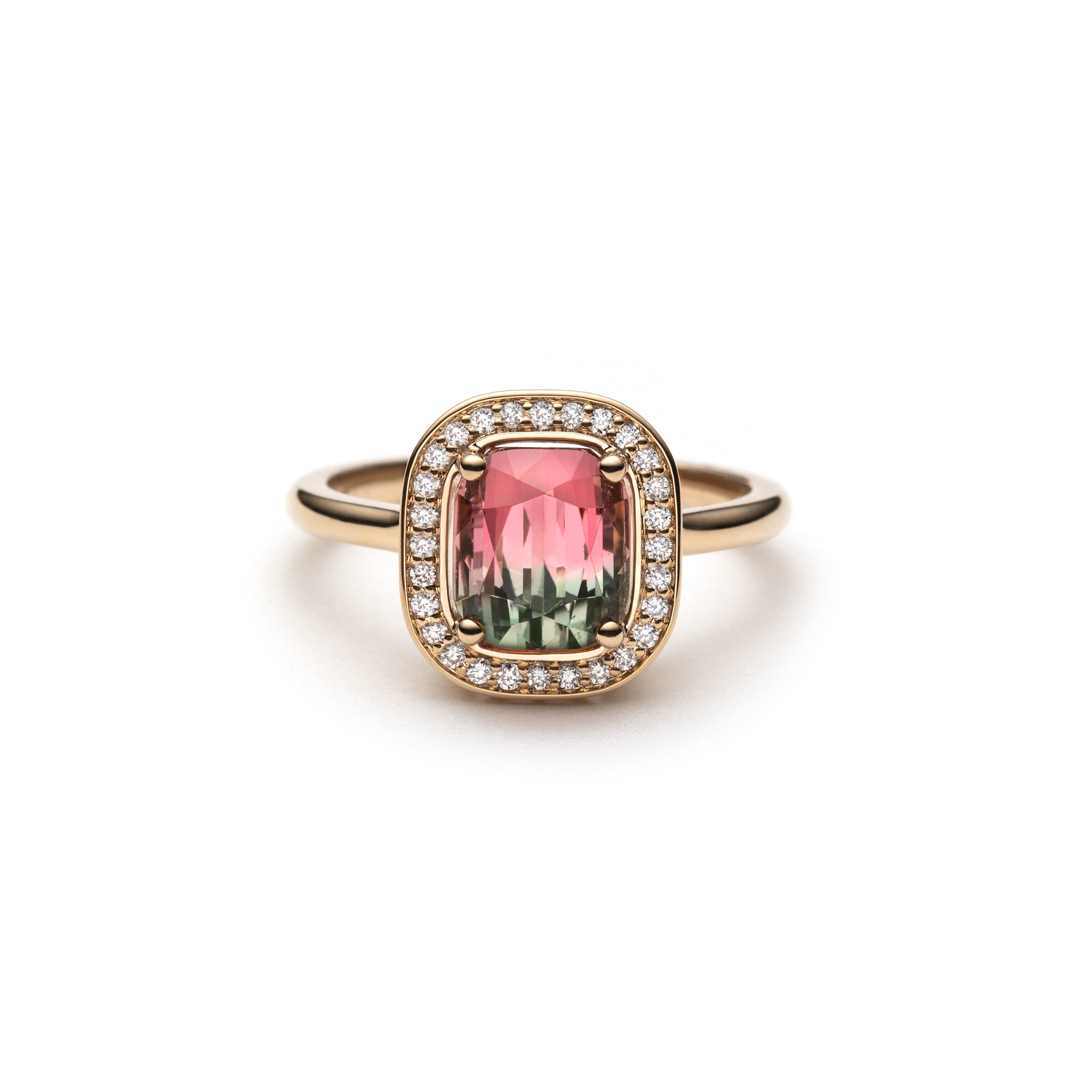 Ring with a green and pink gradient watermelon tourmaline with a Diamond halo set in yellow gold on a white background