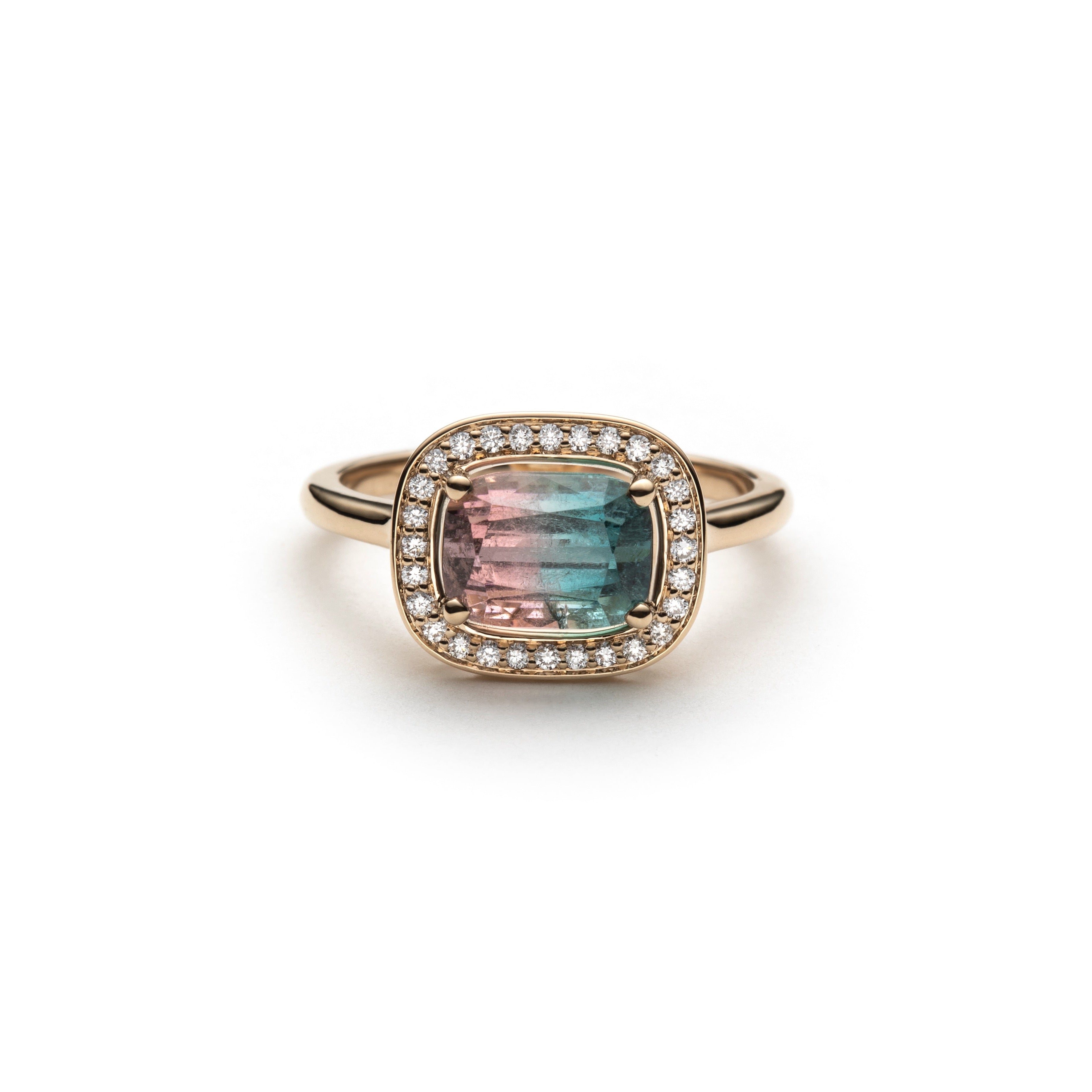 Ring with pink and blue gradiant watermelon tourmaline set east west with a diamond halo on a yellow gold ring on a white background
