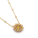 Angled view of a yellow gold sunburst necklace with golden-yellow chrysoberyls, diamond accents and triangular diamond stations.