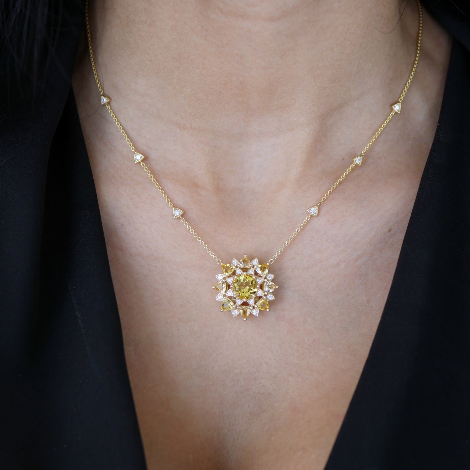 Chrysoberyl and diamond sunburst necklace worn at the neckline, showing the central motif and diamond stations along the yellow gold chain.