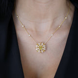 Chrysoberyl and diamond sunburst necklace worn at the neckline, showing the central motif and diamond stations along the yellow gold chain.