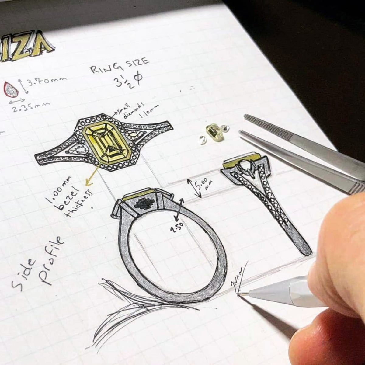 Hand sketching a custom halo ring with a yellow centre stone, showing multiple views and measurements beside loose gemstones and tweezers.