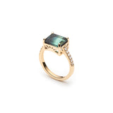 Side view of the blue tourmaline east-west ring, showing the four-prong setting and diamond pavé yellow gold band.