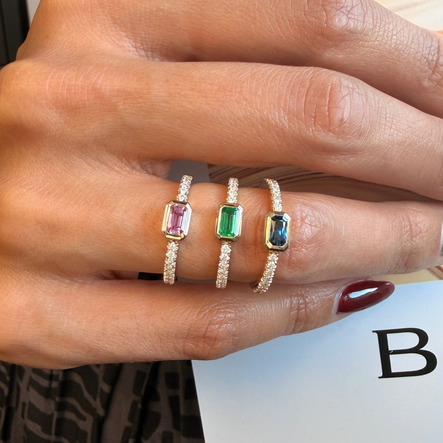 Emerald-cut emerald and diamond pavé stackable ring, worn on a hand.