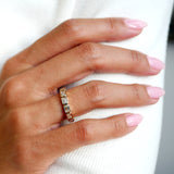 Emerald-cut lab-grown diamond bezel half-eternity ring in yellow gold, worn on a hand.