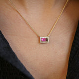 Yellow gold necklace featuring an emerald cut watermelon tourmaline set east-west with a diamond halo, worn around the neck.