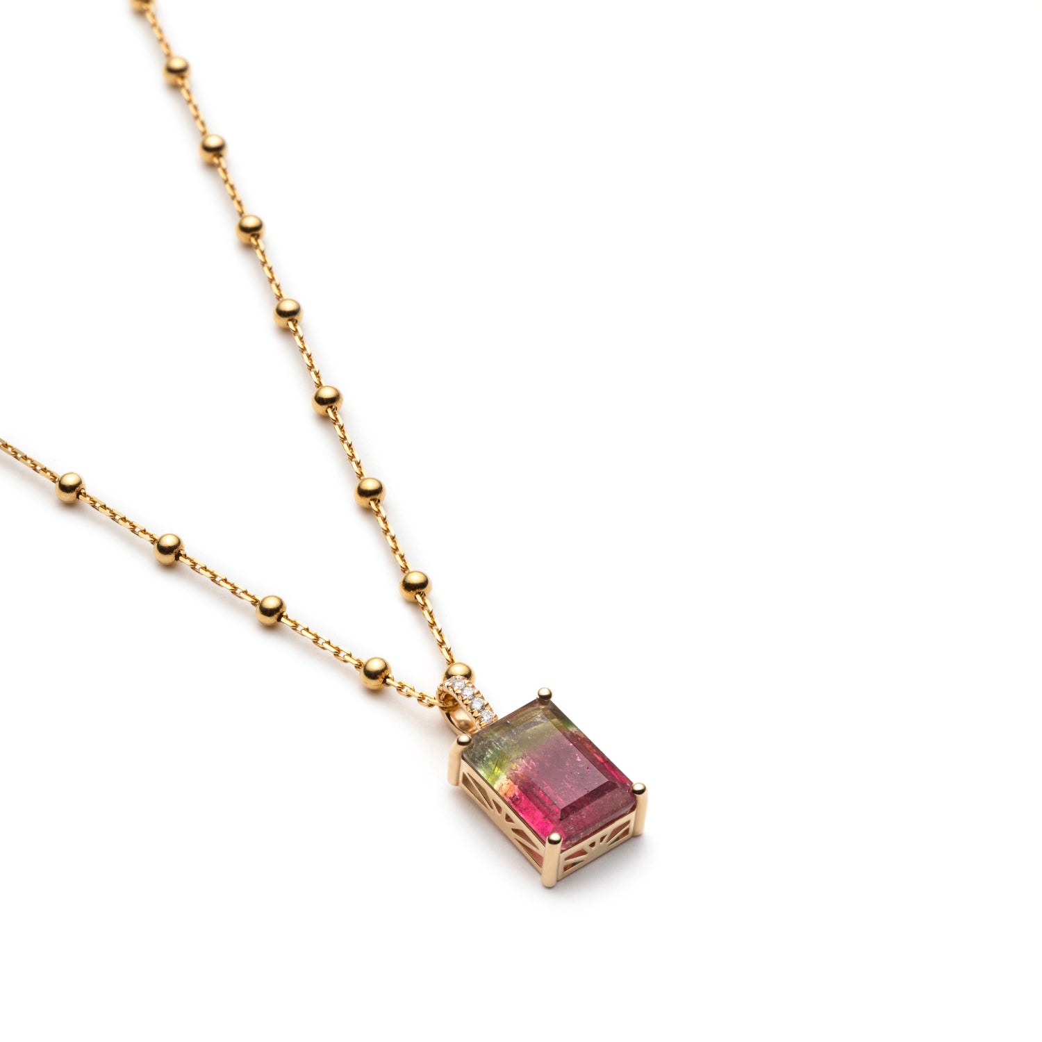 Detail of the emerald-cut watermelon tourmaline and diamond pavé bail on a gold bead station chain.