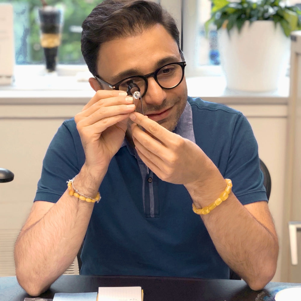 Jivan Yeramian inspecting a diamond with a jeweler’s loupe at his workbench.