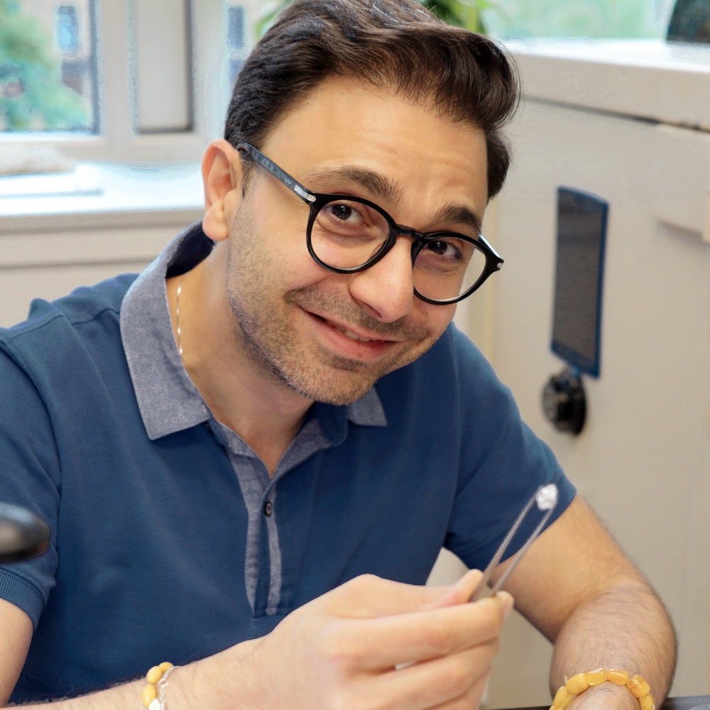 Jivan Yeramian, founder of Jewelry Design House, holding a diamond in tweezers at his workbench.