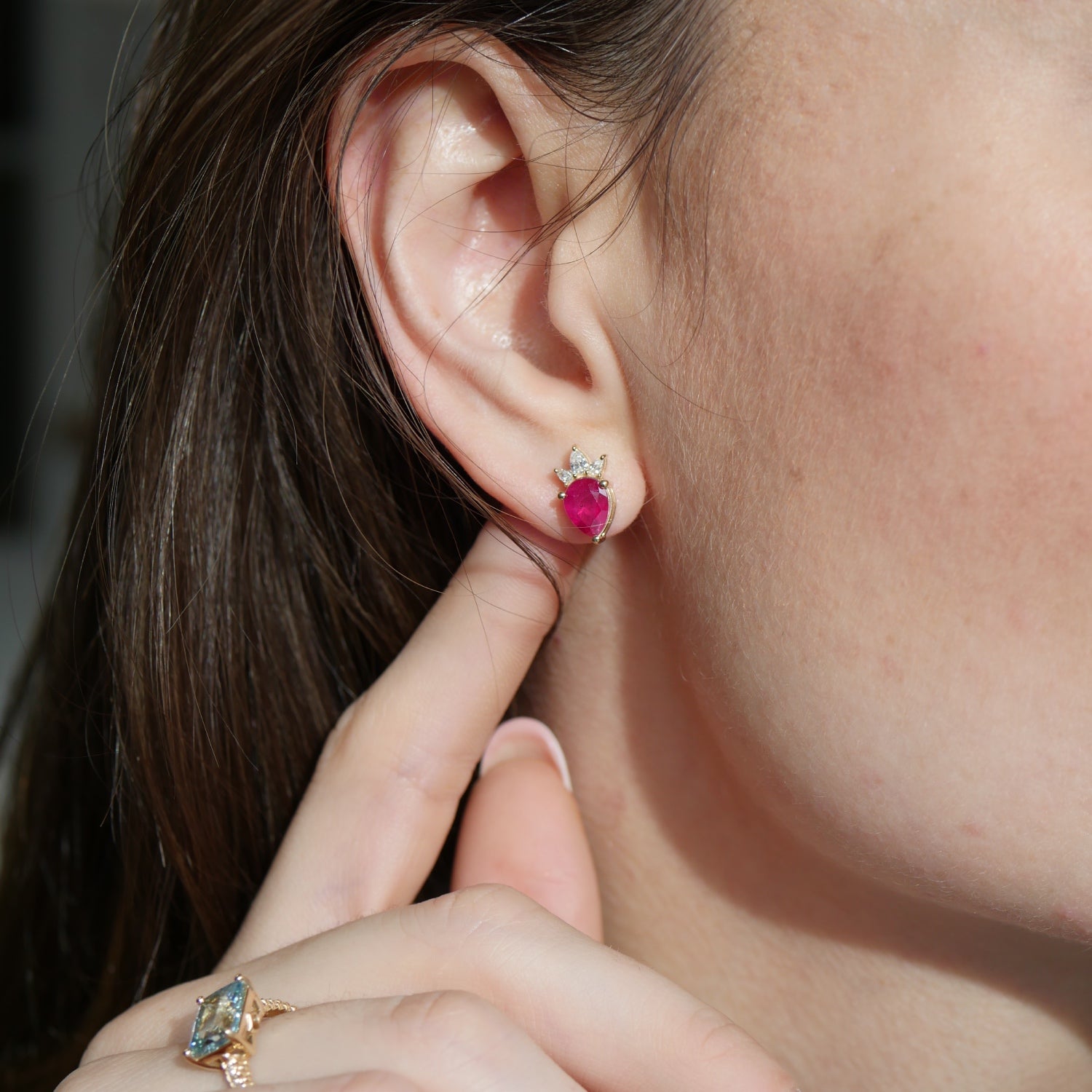 Pear-shaped ruby stud earring with a diamond tiara in 14K yellow gold, worn on an ear.