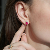 Pear-shaped ruby stud earring with a diamond tiara in 14K yellow gold, worn on an ear.