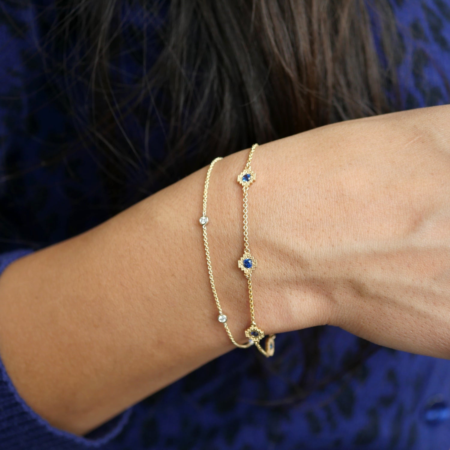 Gold bracelet featuring five round blue sapphires in mini step motifs, worn on the wrist.